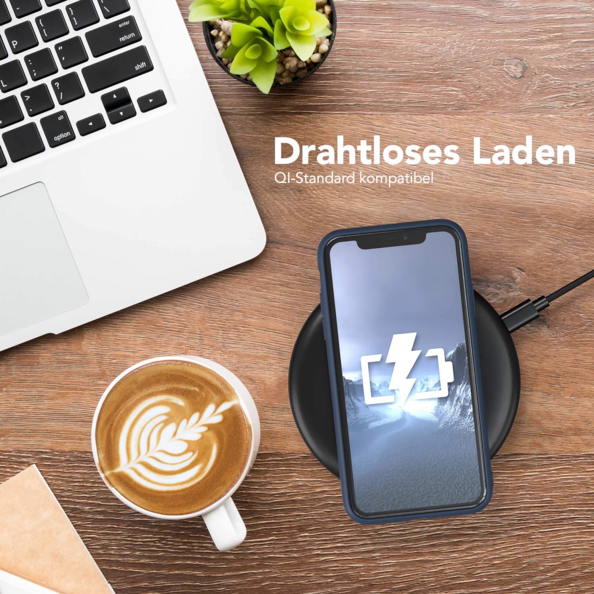 Ein Telefon wird auf einem kabellosen Ladegerät aufgeladen, neben einem Laptop und einer Kaffeetasse mit Latte Art.