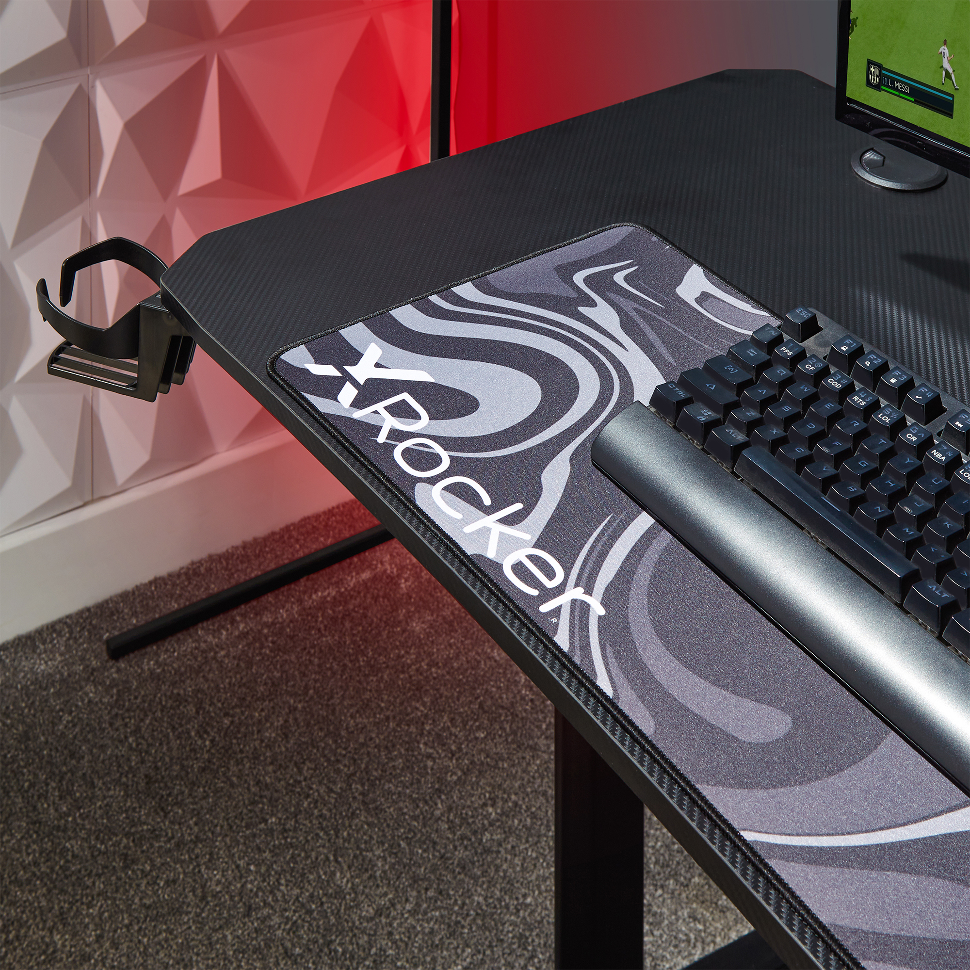 Gaming-Setup mit Schreibtisch, Mauspad, Tastatur und Monitorständer. Der Schreibtisch ist schwarz.