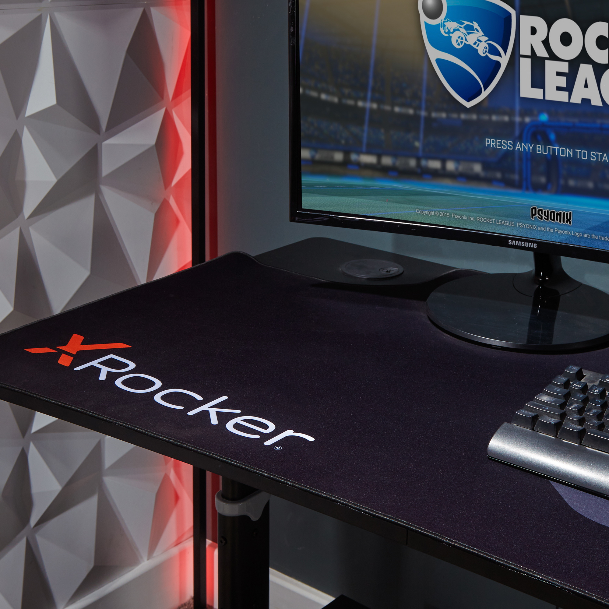 Ein schwarzer Schreibtisch mit einem Computermonitor, einer Tastatur und einem Gaming-Mauspad.