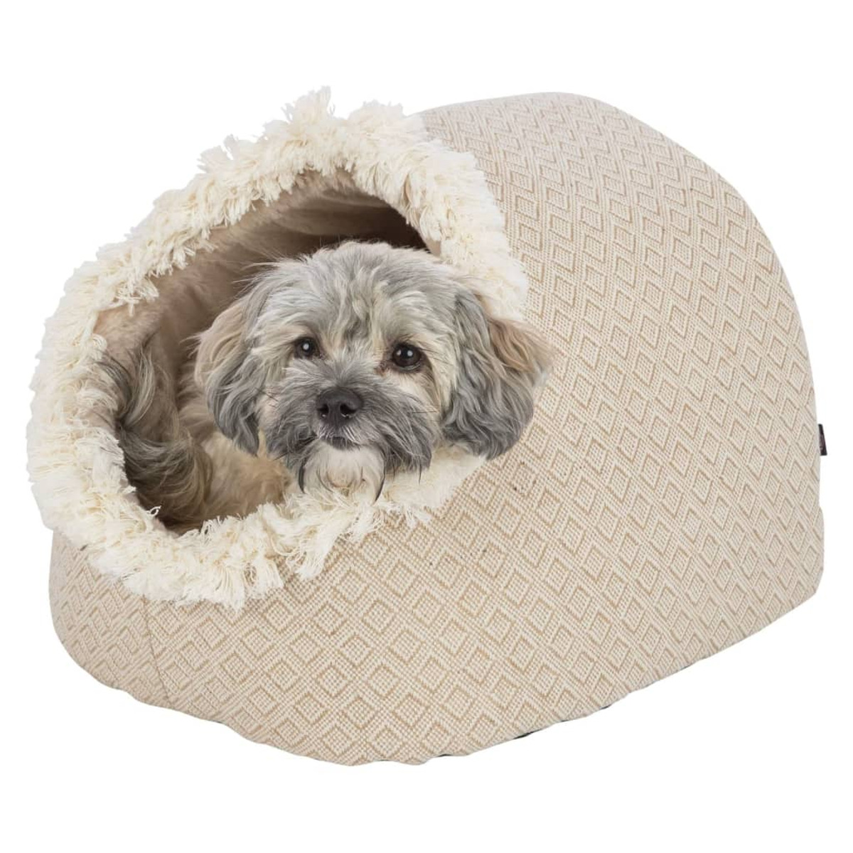 Un cane sbuca da una cuccia beige con finiture color crema, su sfondo bianco.