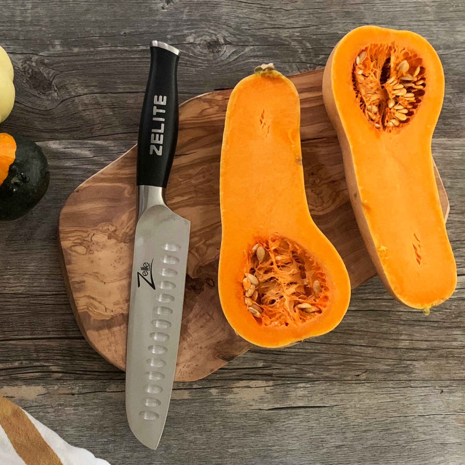 Ein Butternusskürbis ist halbiert, ein Messer liegt auf einem Holzschneidebrett.