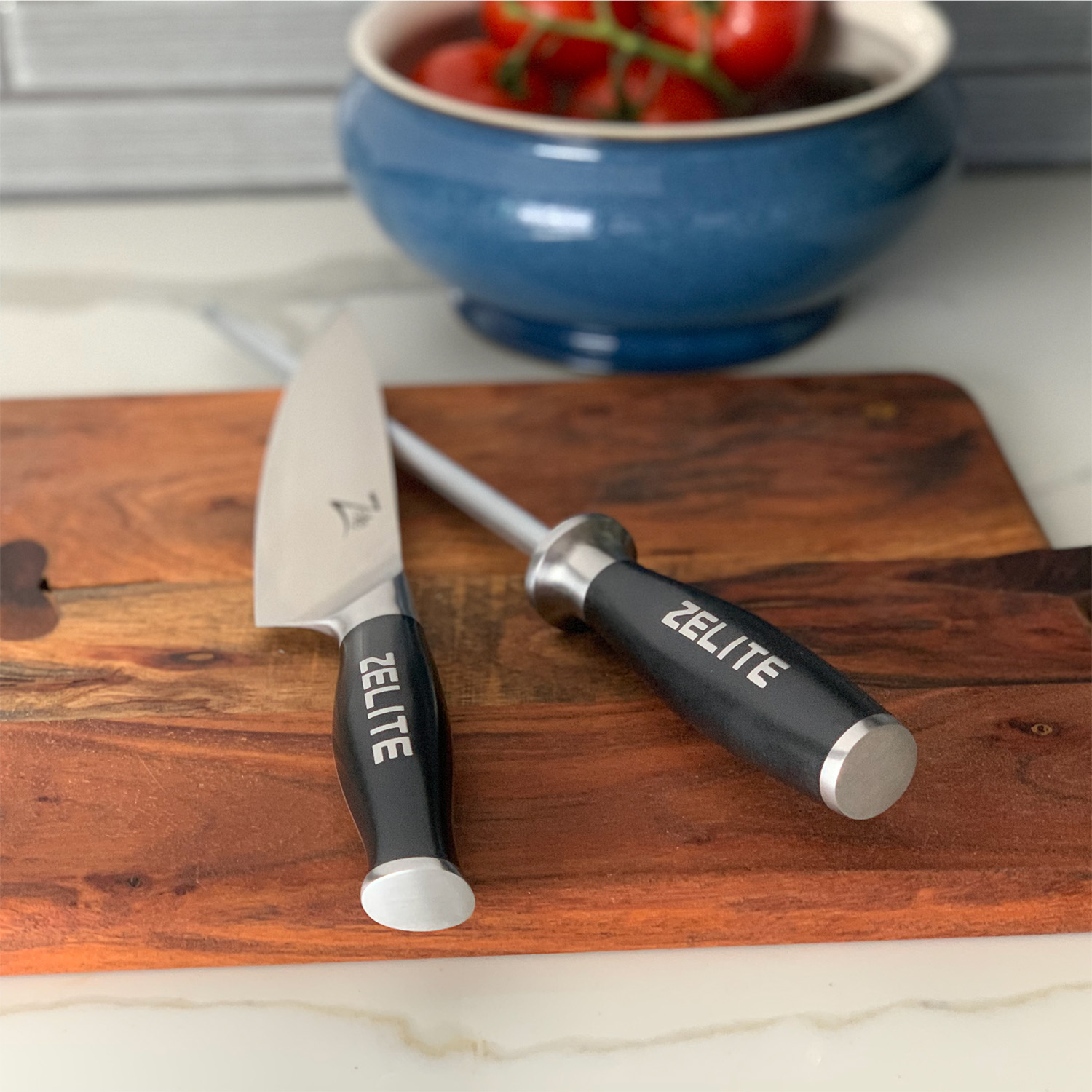Messer, Wetzstahl und Tomatenschüssel auf einem Holzschneidebrett.