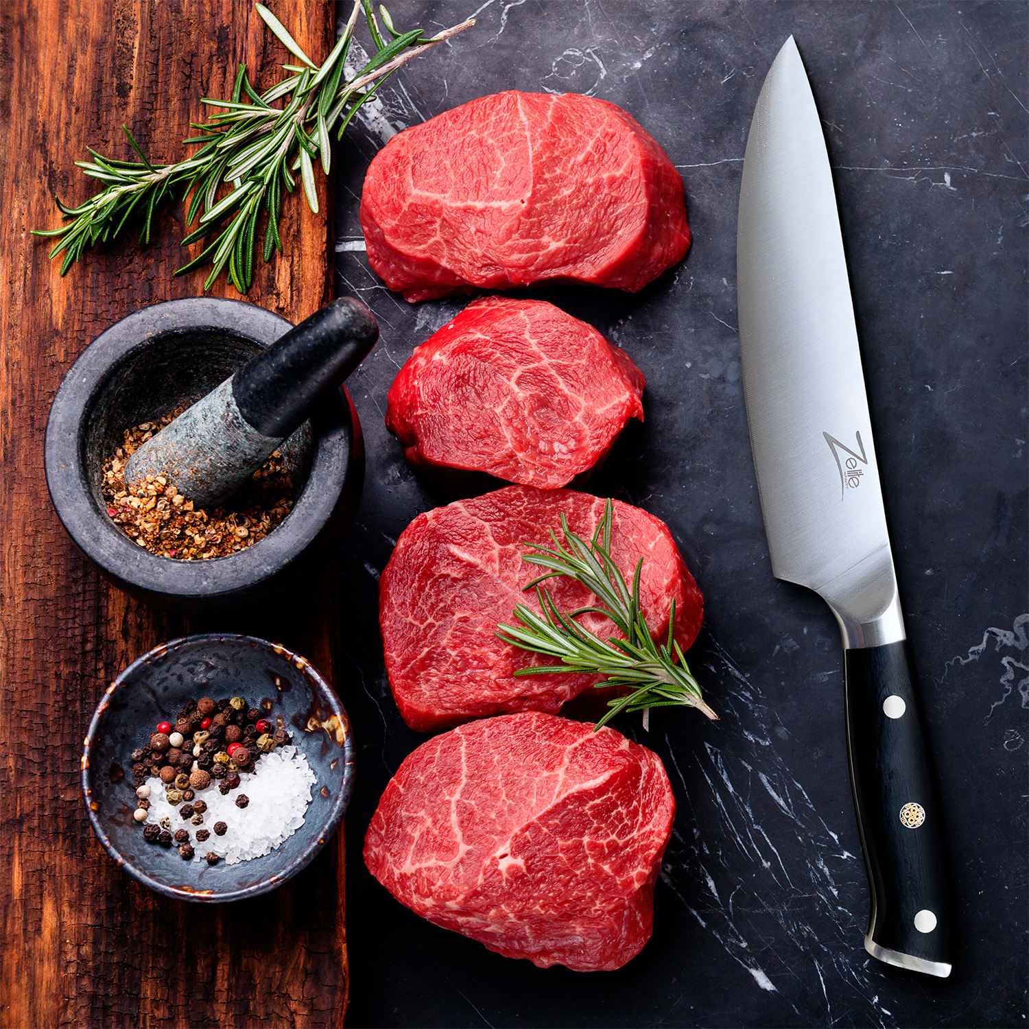 Vier rohe Steaks, Messer, Mörser, Schüssel mit Pfefferkörnern und Salz, Rosmarin auf dunkler Fläche.