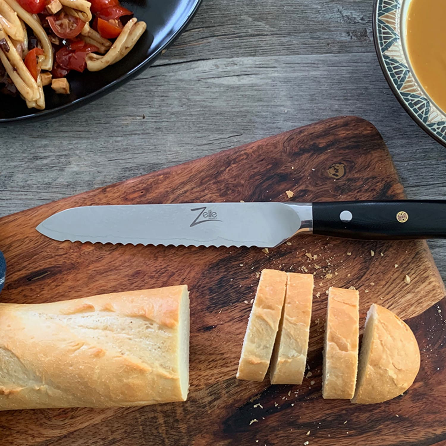 Ein Messer auf einem Schneidebrett mit Brot. Pasta und eine Schüssel Suppe sind ebenfalls auf dem Tisch.