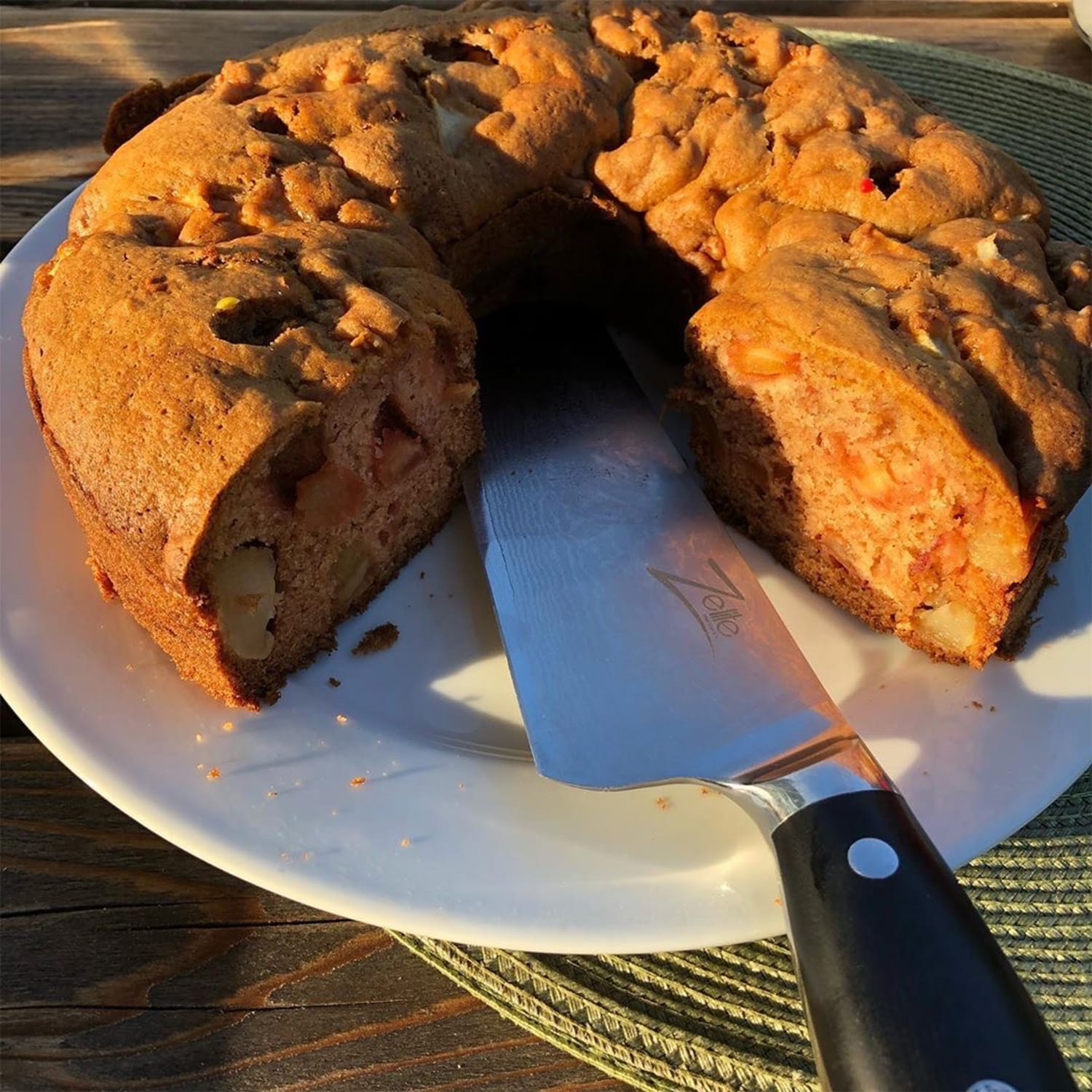 Ein teilweise geschnittener Kuchen mit einem Messer auf einem weißen Teller.