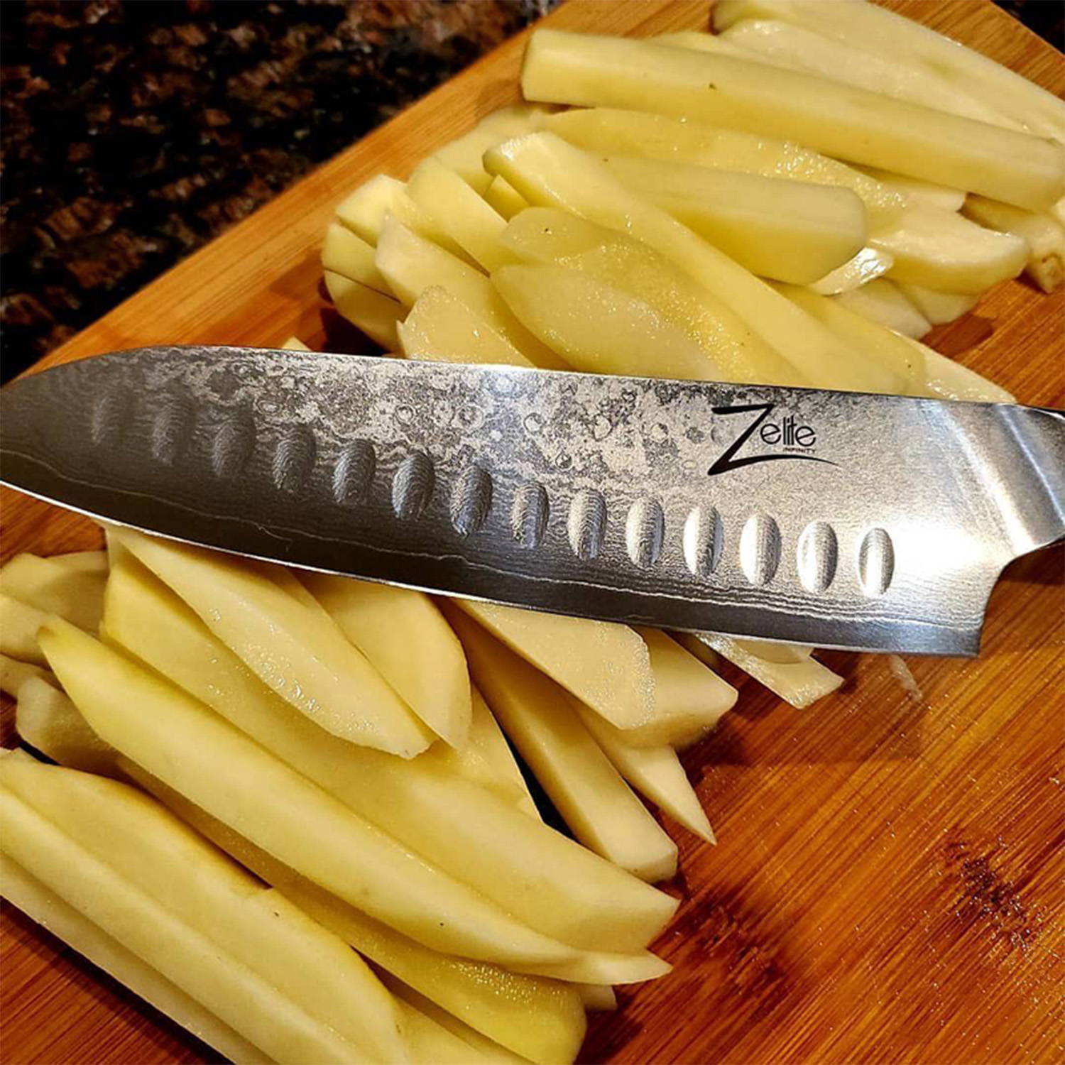 Ein ZELITE-Messer mit Kartoffeln auf einem hölzernen Schneidebrett. Dunkler Hintergrund.