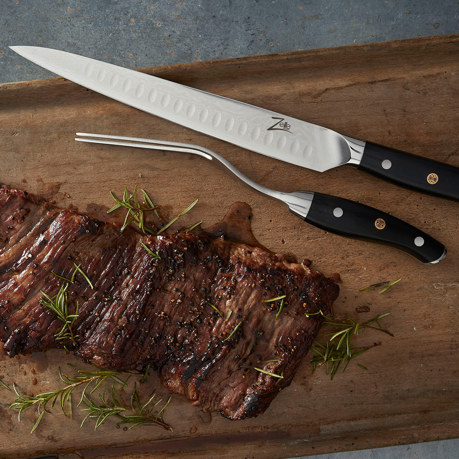 Ein Holzschneidebrett mit Steak und einer Tranchiergabel. Rosmarinzweige sind um das Essen verstreut.