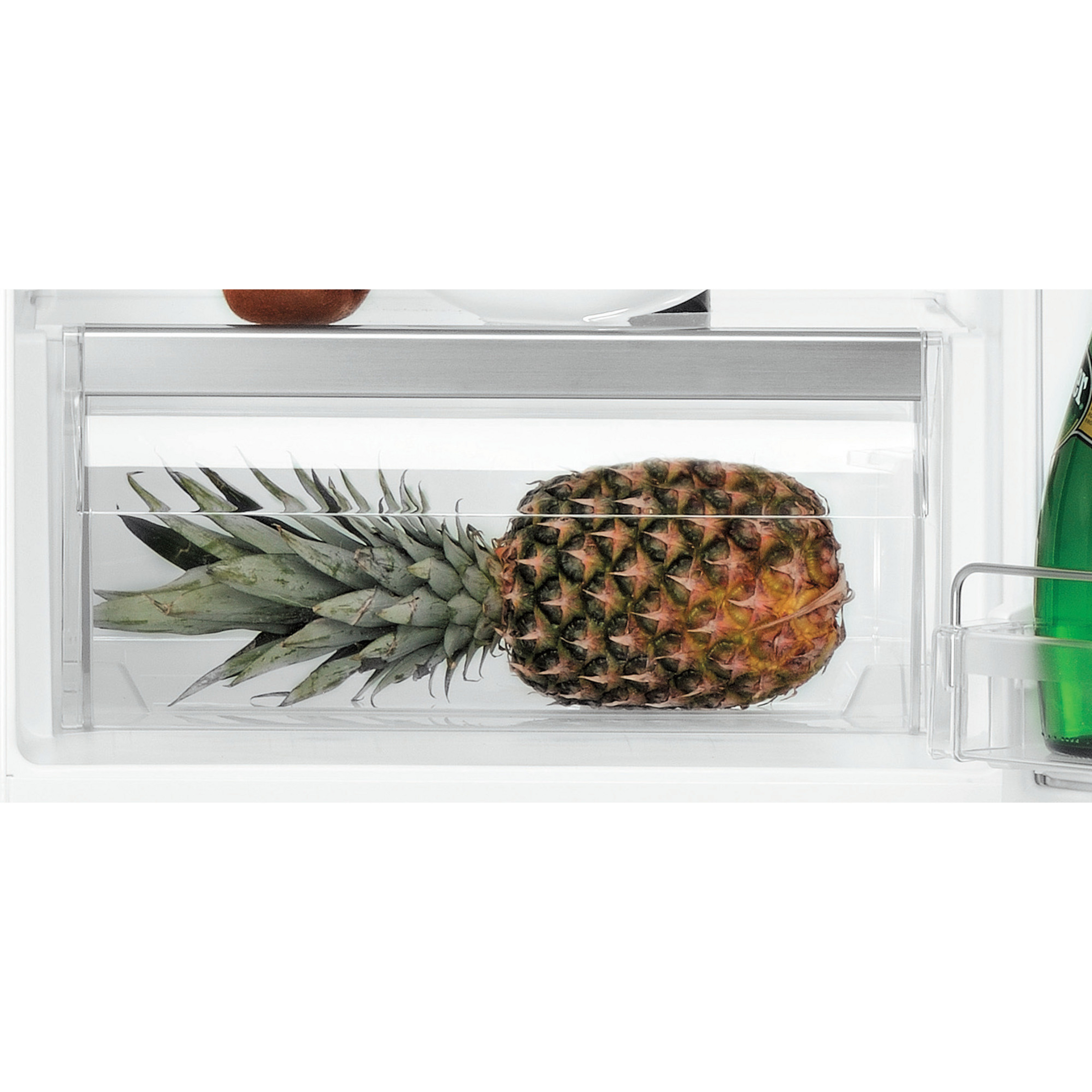 Eine Ananas in einer Kühlschublade. Eine Flasche Champagner ist rechts.