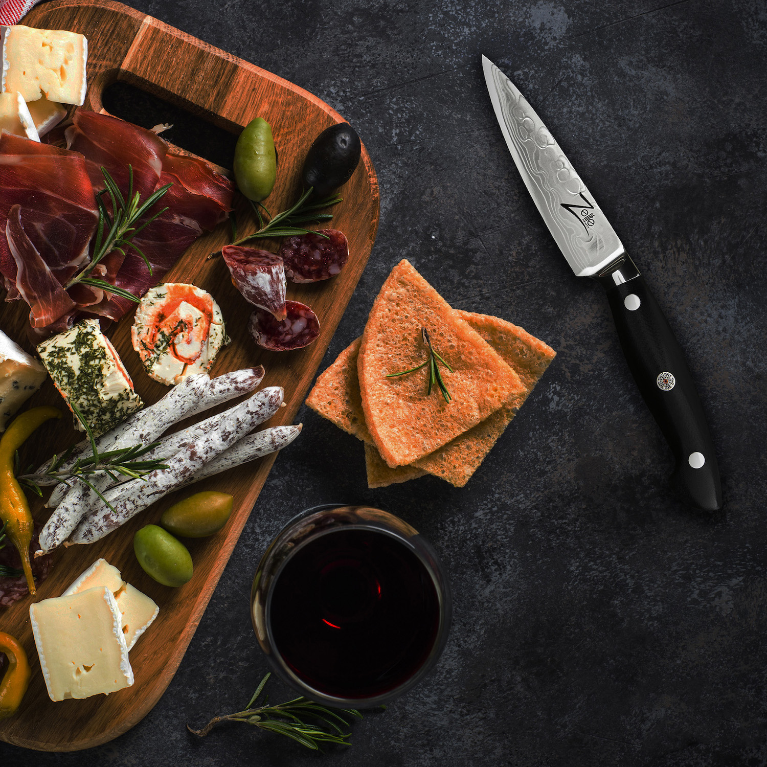 Charcuterie-Brett mit Fleisch, Käse, Crackern, Oliven und einem Glas Rotwein.