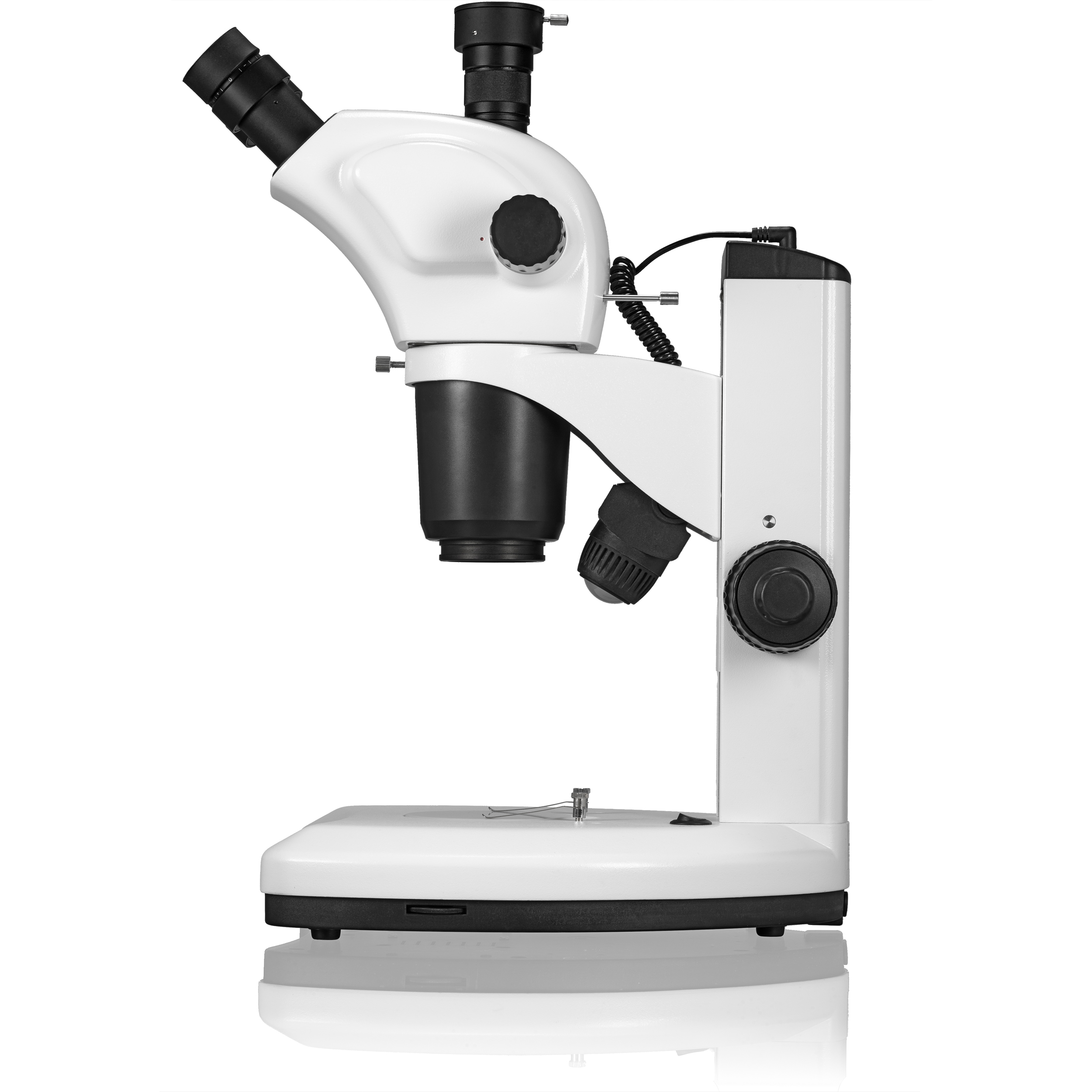 Un microscopio blanco con lentes y controles negros está sobre una superficie blanca. La lente apunta a la izquierda.