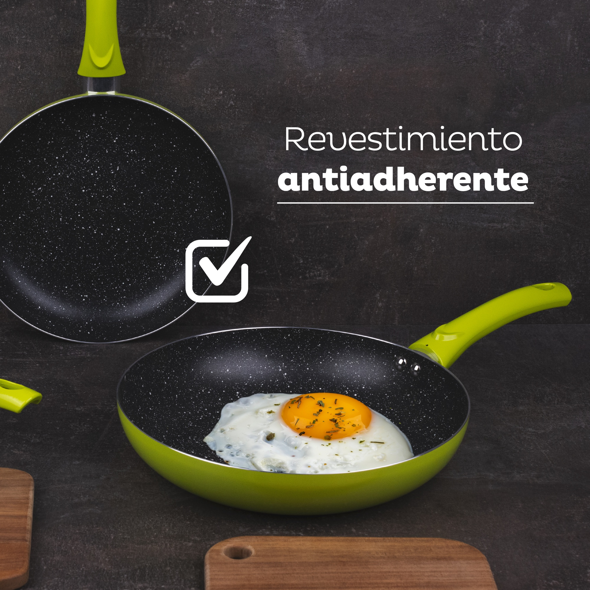 Dos sartenes verdes con un huevo frito en una. Las sartenes están sobre una superficie oscura. Los mangos son verdes.