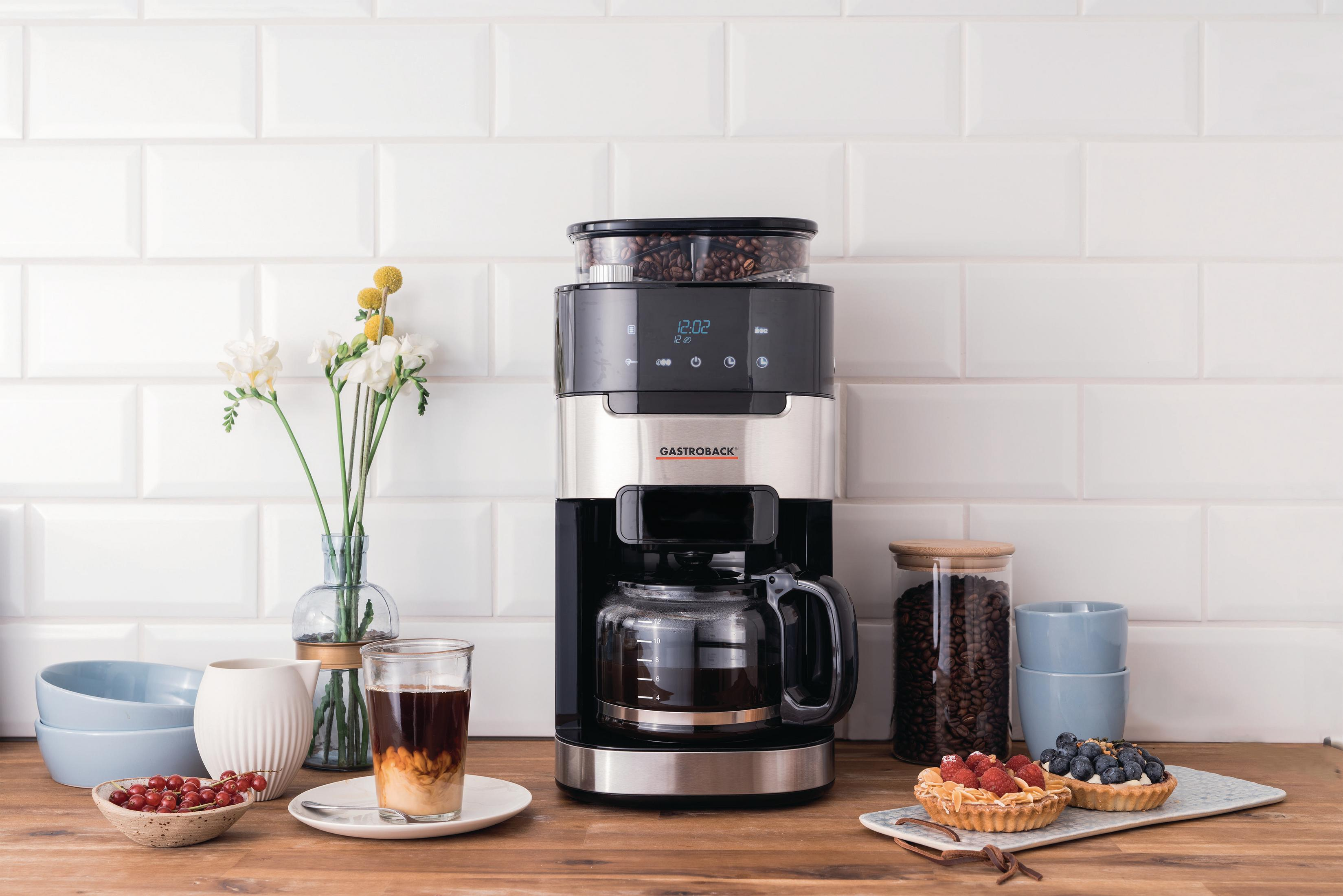 Ekspres do kawy z młynkiem, szklaną karafką i ziarnami kawy. Serwowane z ciastami i mlekiem.