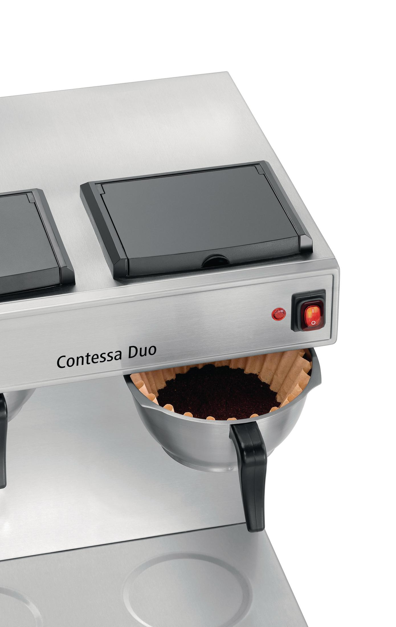 Macchina da caffè con due filtri da caffè con fondi. Macchina argentata, coperchi e manico neri. Sfondo bianco.
