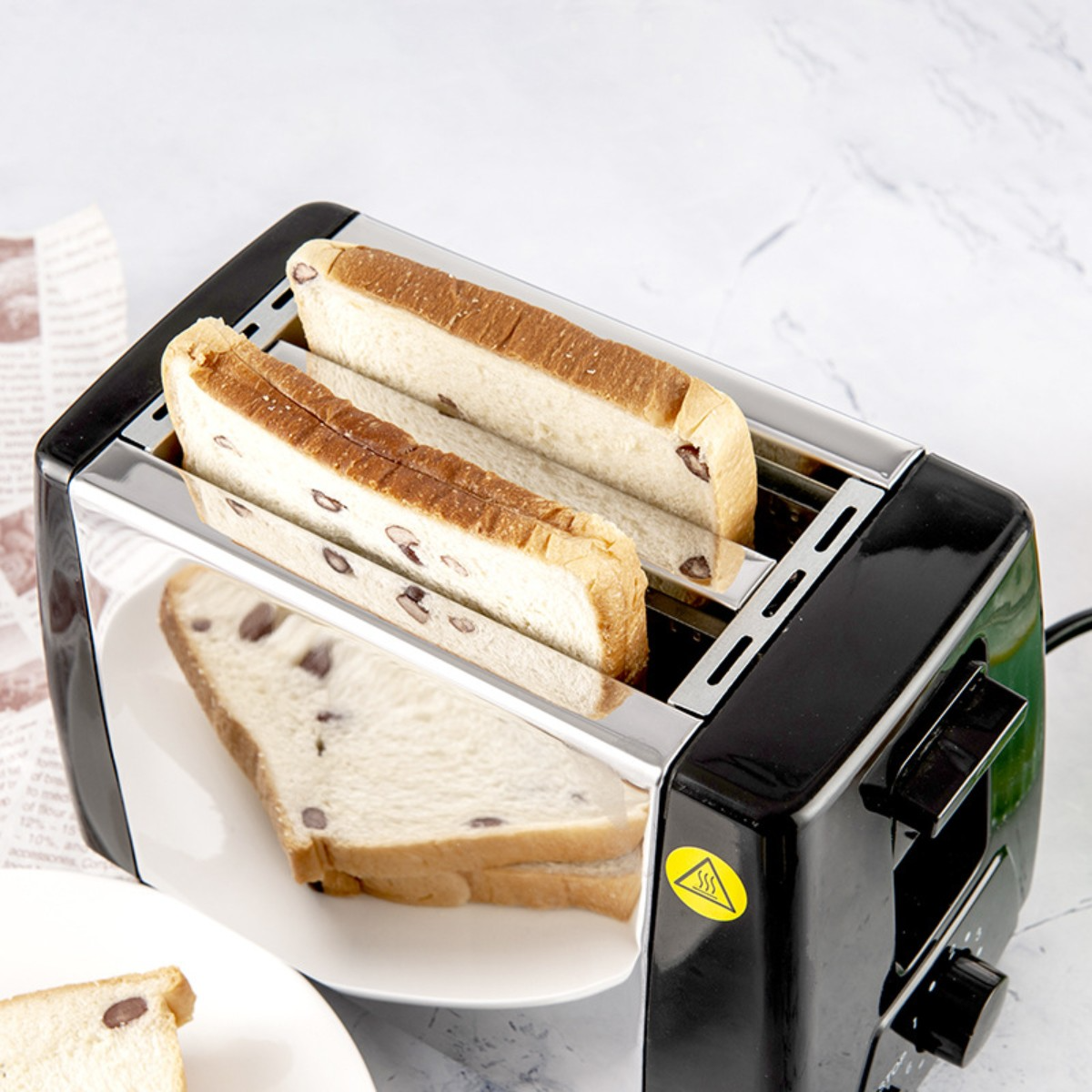Toaster mit zwei Brotscheiben, mit einem Teller mit einer Brotscheibe.