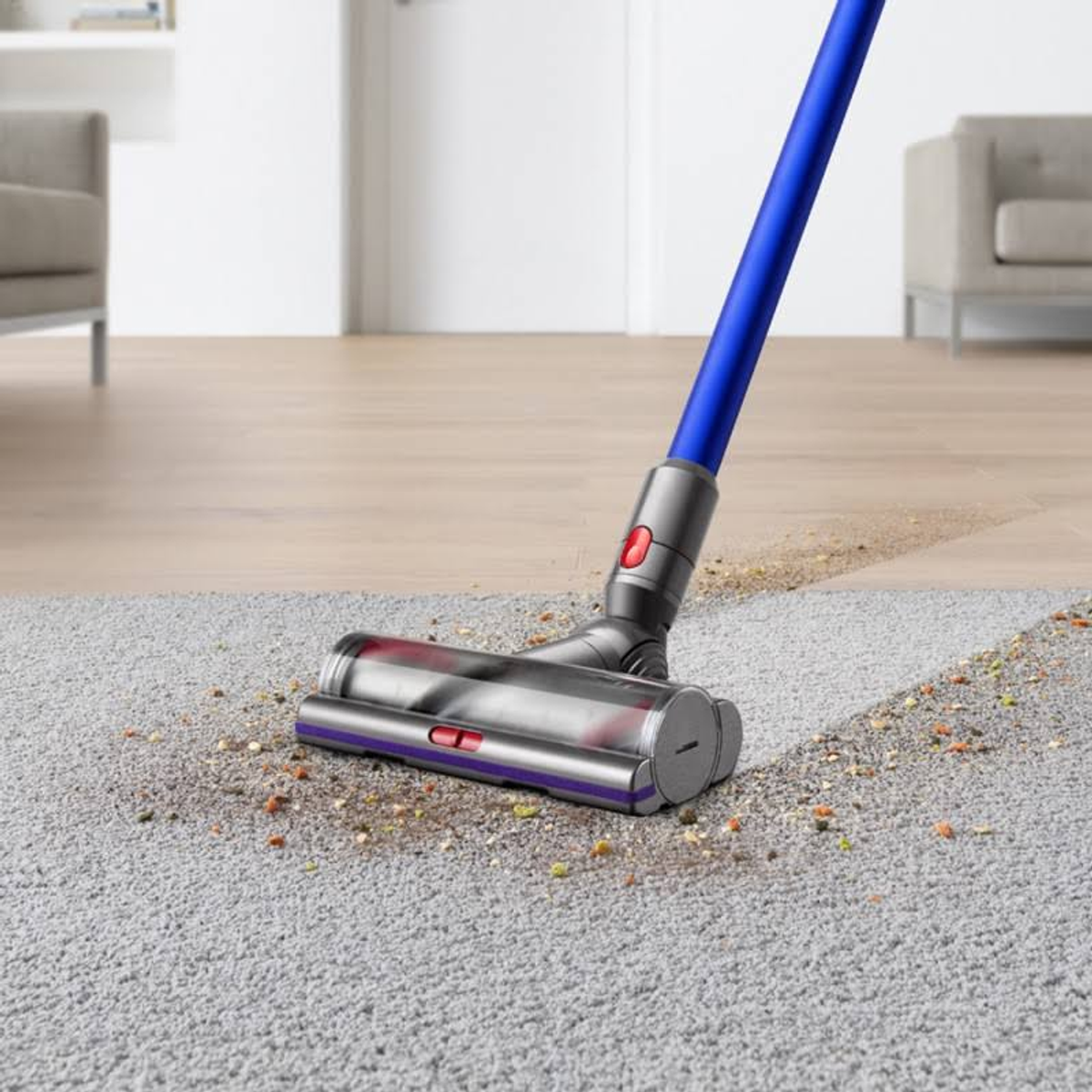 Staubsauger reinigt Teppich. Blauer Griff, silberner Kopf, nimmt Schmutz auf.