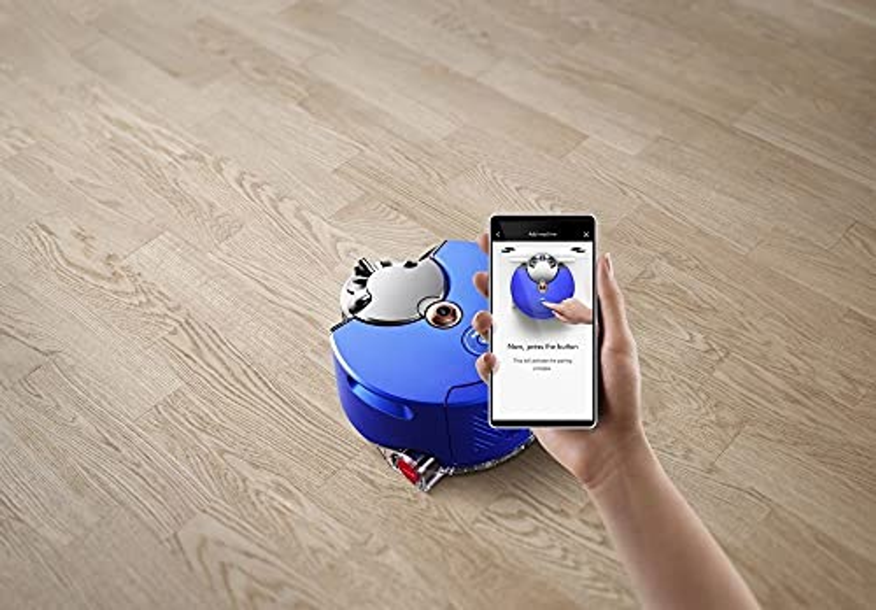 Eine Hand, die ein Telefon hält, das eine App zeigt, die einen Roboterstaubsauger steuert.