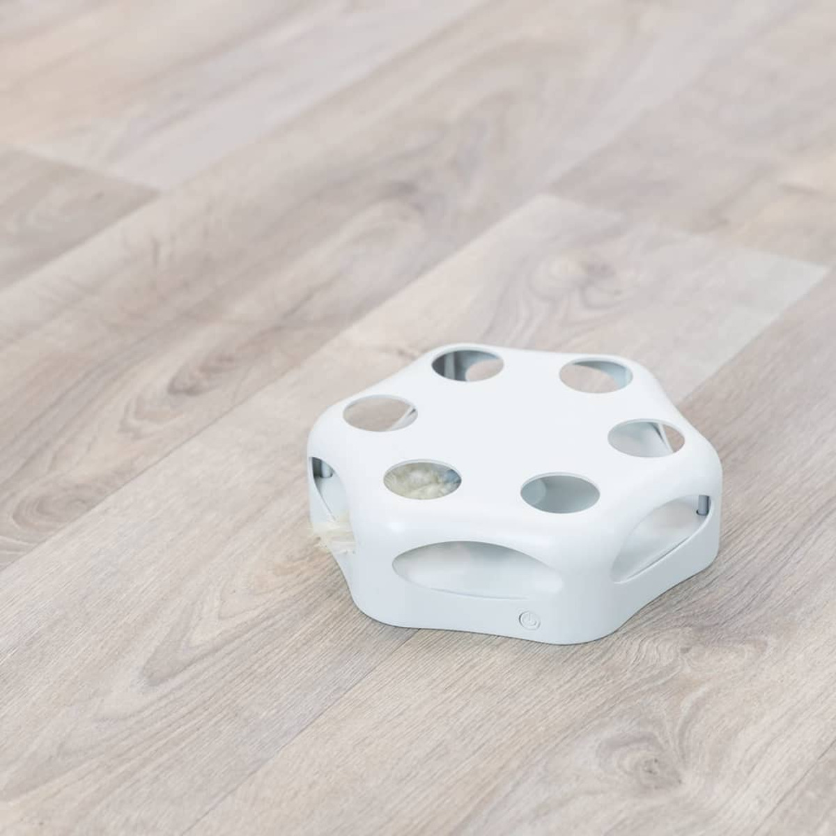 Biała zabawka dla kota z wieloma otworami.