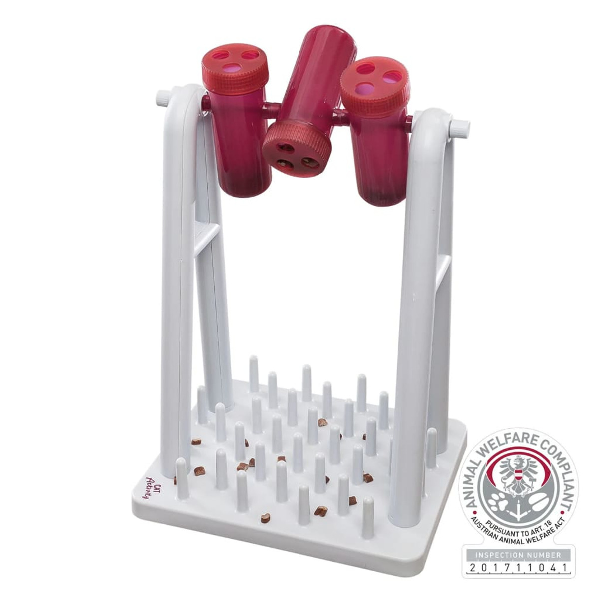 Biała zabawka dla kota z czerwonymi rurkami i białą podstawą z małymi brązowymi kawałkami jedzenia.