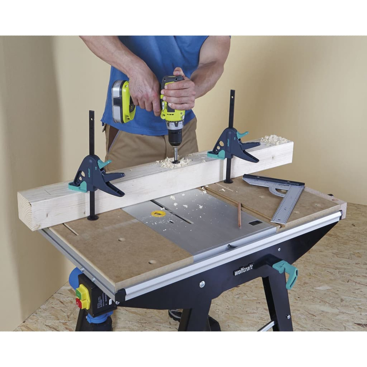 Mann, der eine Bohrmaschine auf Holz auf einer Werkbank benutzt. Klemmen sichern Holz. Werkbank hat eine Säge und ein Lineal.