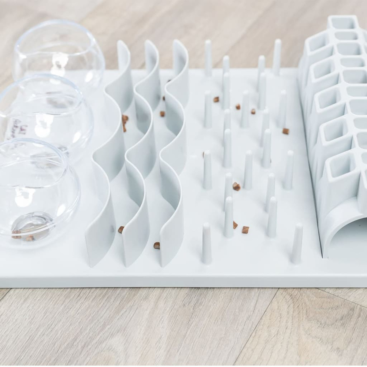 Un puzzle bianco per cani con pezzi di cibo su un pavimento in legno.