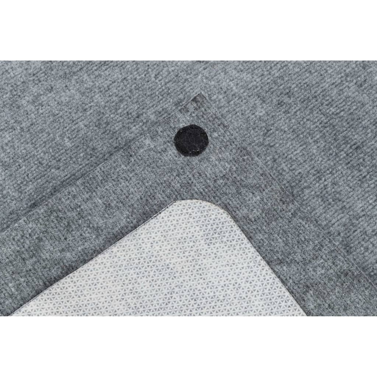 Primo piano di pezzi di tappeto grigio. Un pezzo è capovolto, mostrando il lato inferiore bianco con un motivo strutturato.