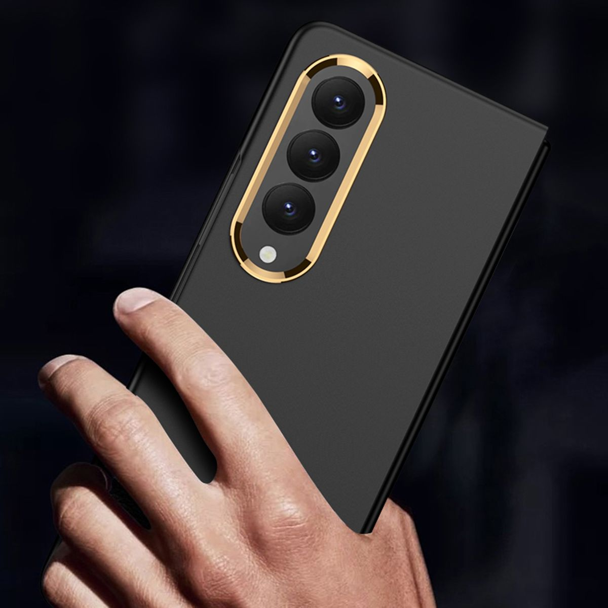 Ein geschlossenes, schwarzes Telefon mit goldgerahmter Kamera. In der Hand gehalten, dunkler Hintergrund.