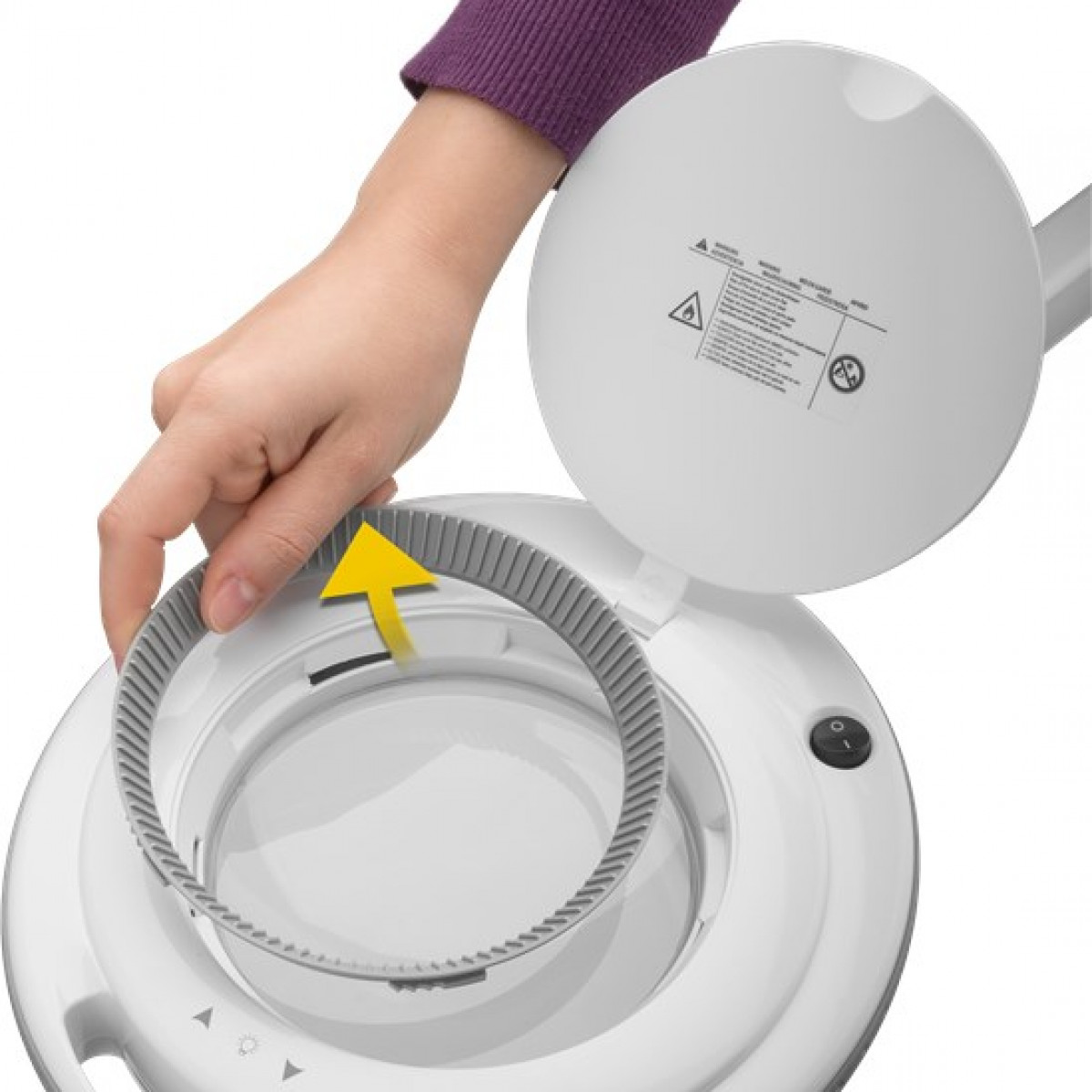 Eine Hand öffnet eine Lupenlampe, wobei ein Ring entfernt wird, weißer Hintergrund.