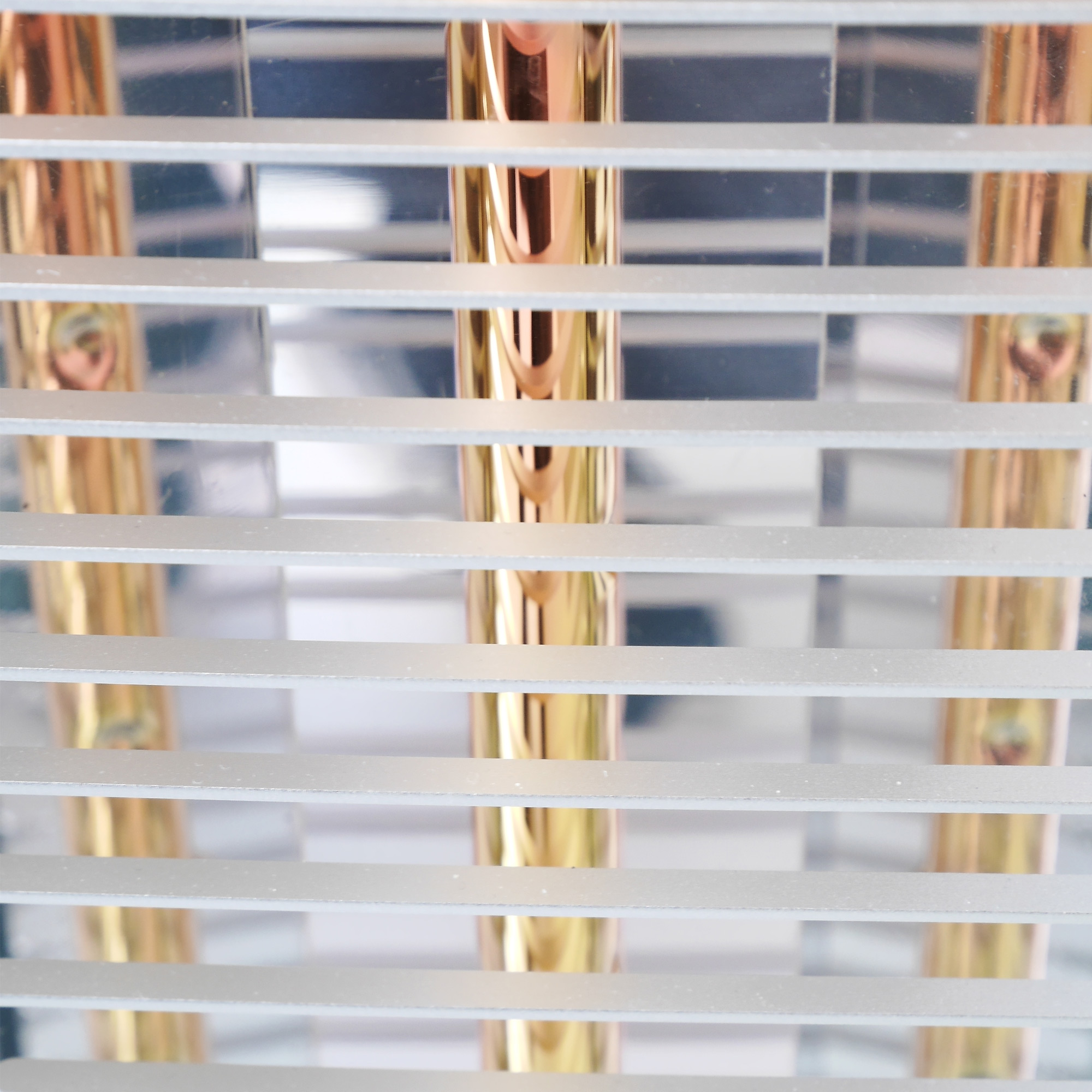 Nahaufnahme von goldenen und silbernen Metallstangen, durch eine Reihe von silbernen horizontalen Stangen betrachtet.