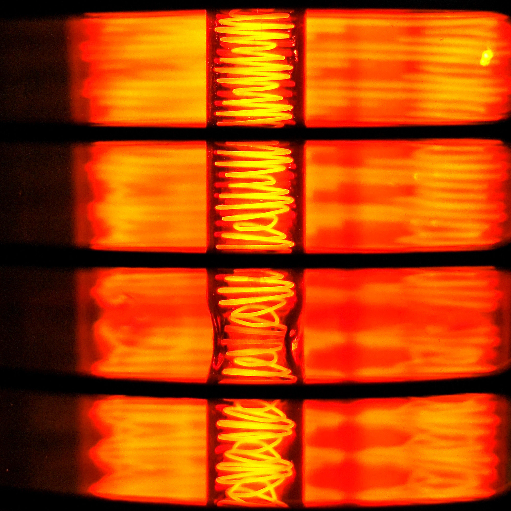 Nahaufnahme von glühenden orangefarbenen Heizelement-Spulen, Spiegelbild.