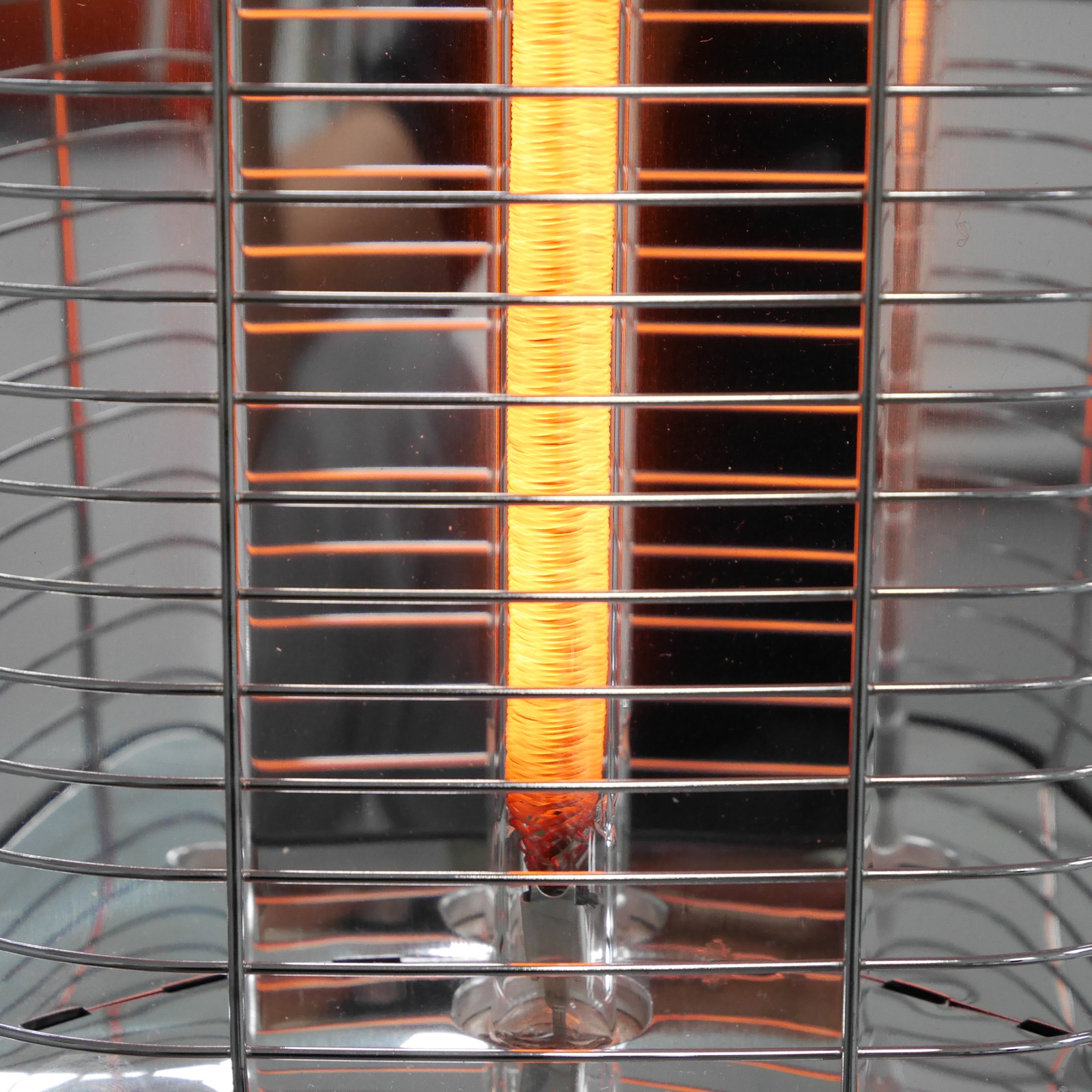 Nahaufnahme eines Terrassenheizers mit glühendem orangefarbenem Element, umgeben von einem Metallkäfig.