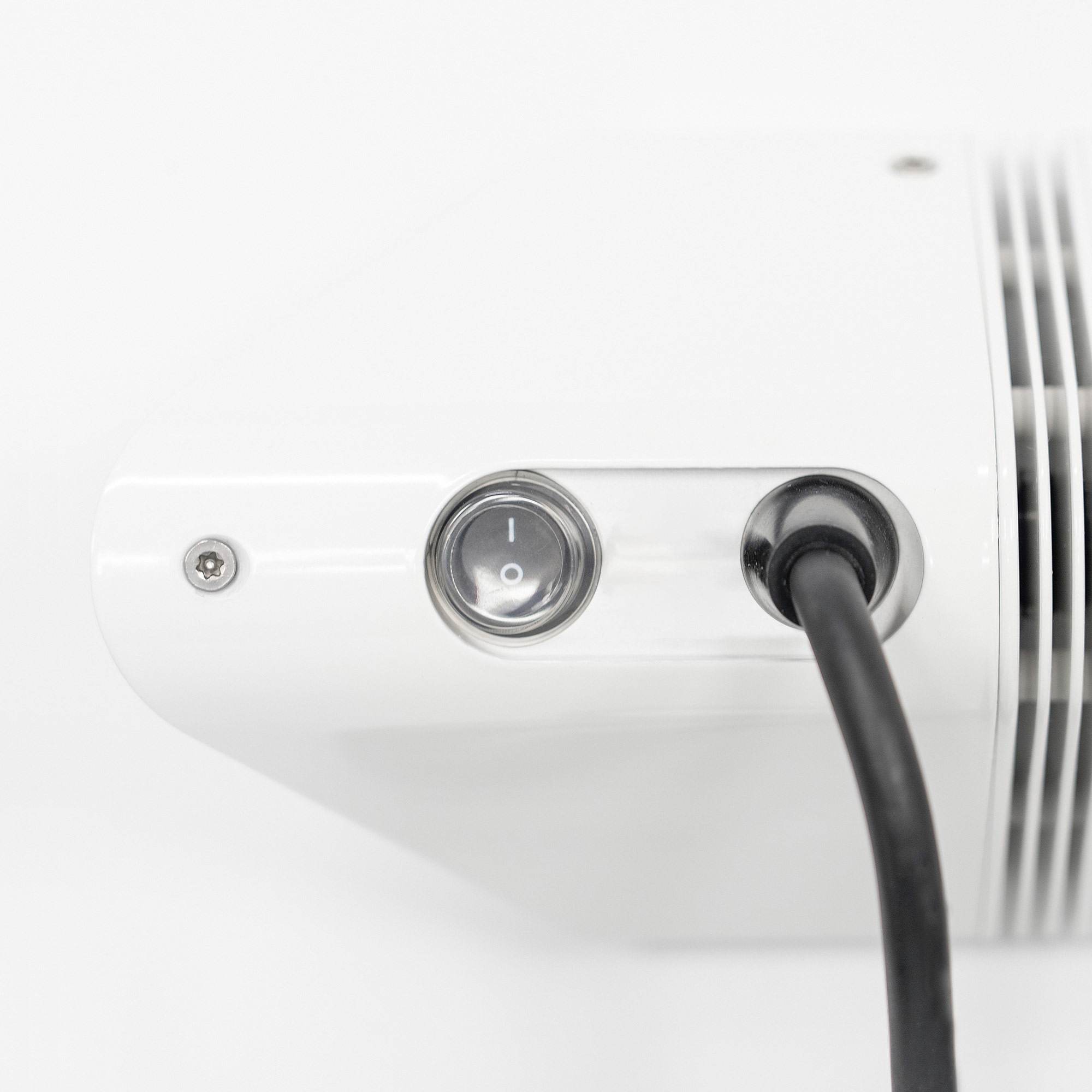 Nahaufnahme der Unterseite eines weißen elektronischen Geräts mit Ein-Aus-Schalter und schwarzem Netzkabel.