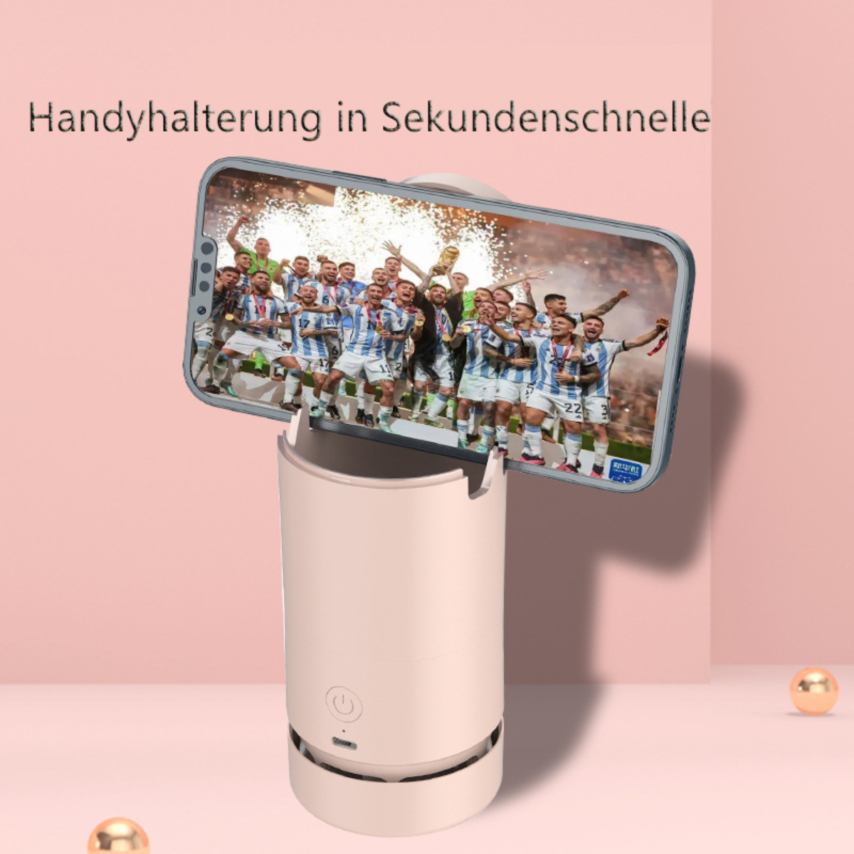 Un teléfono en un soporte muestra un video de un equipo celebrando, sobre un fondo rosa.