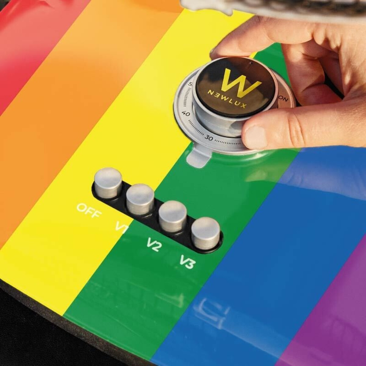 Un panel de control, con colores del arcoíris, con botones etiquetados V1, V2, V3 y un dial numérico.