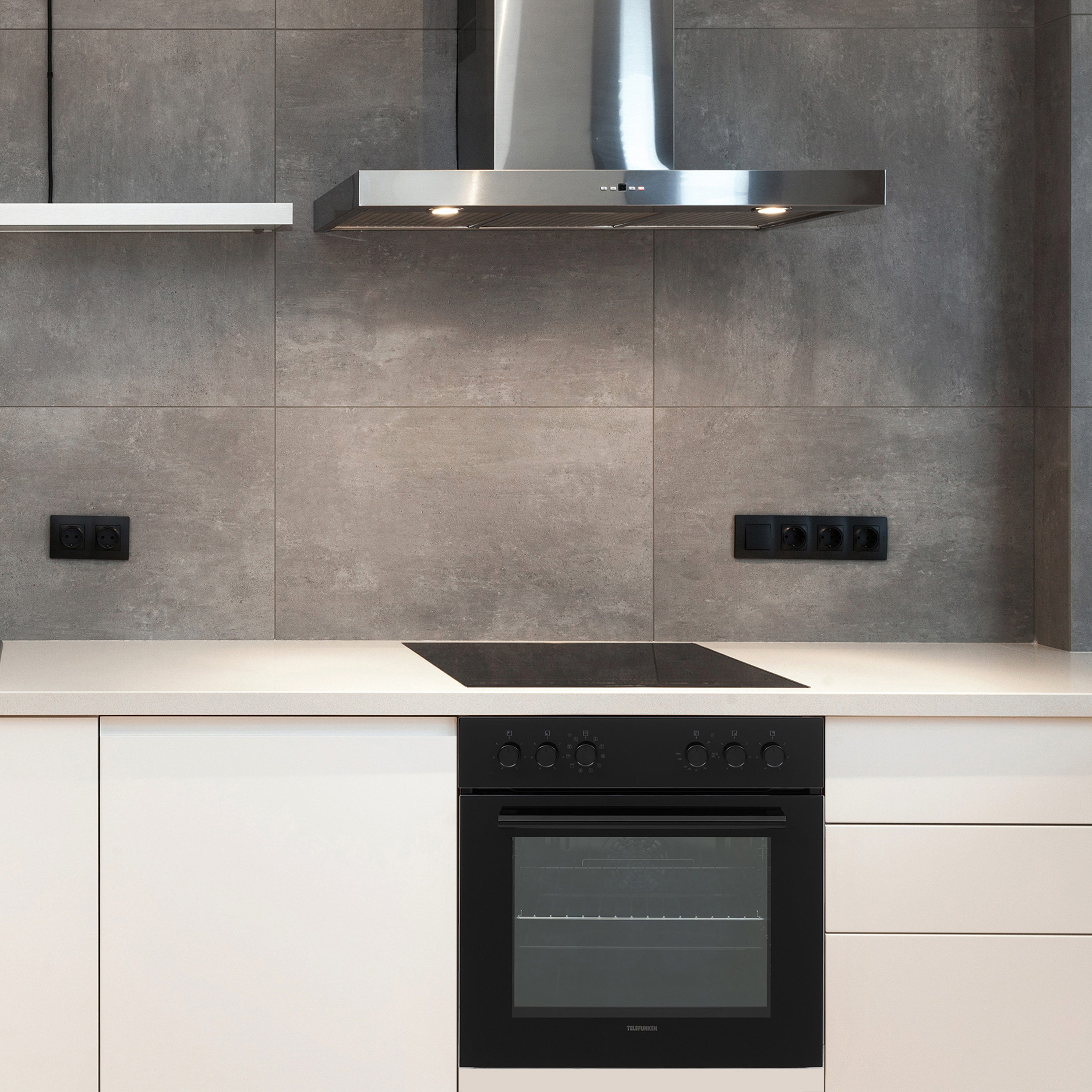 Modernes Kücheninterieur mit weißen Schränken, schwarzem Ofen und grauer Kachelwand.
