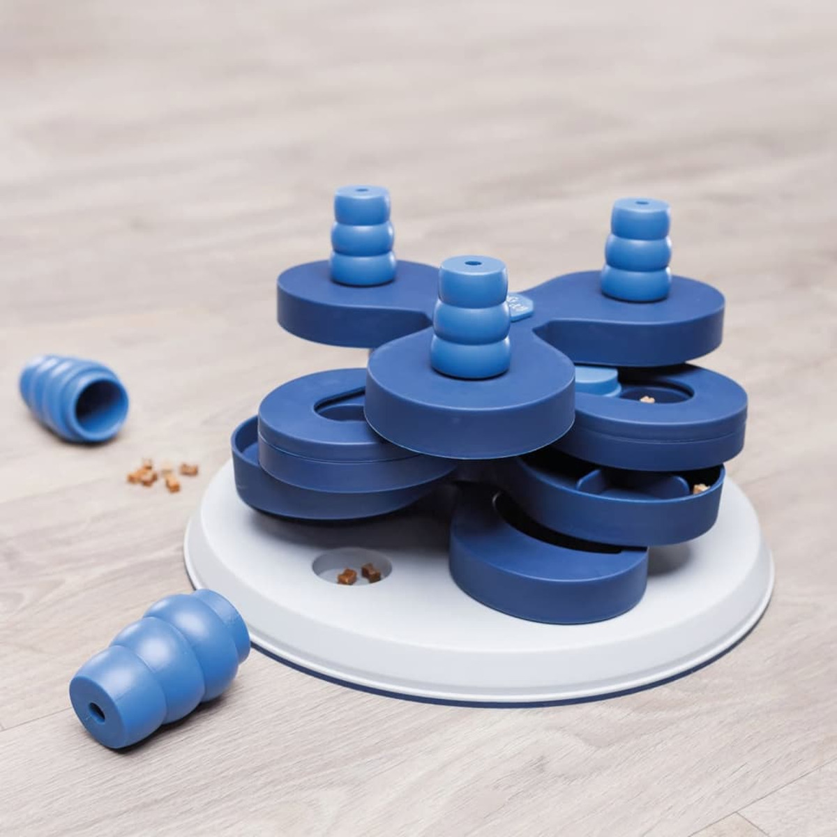 Giocattolo puzzle blu per cani con livelli rotanti. Cibo sparso sul pavimento.