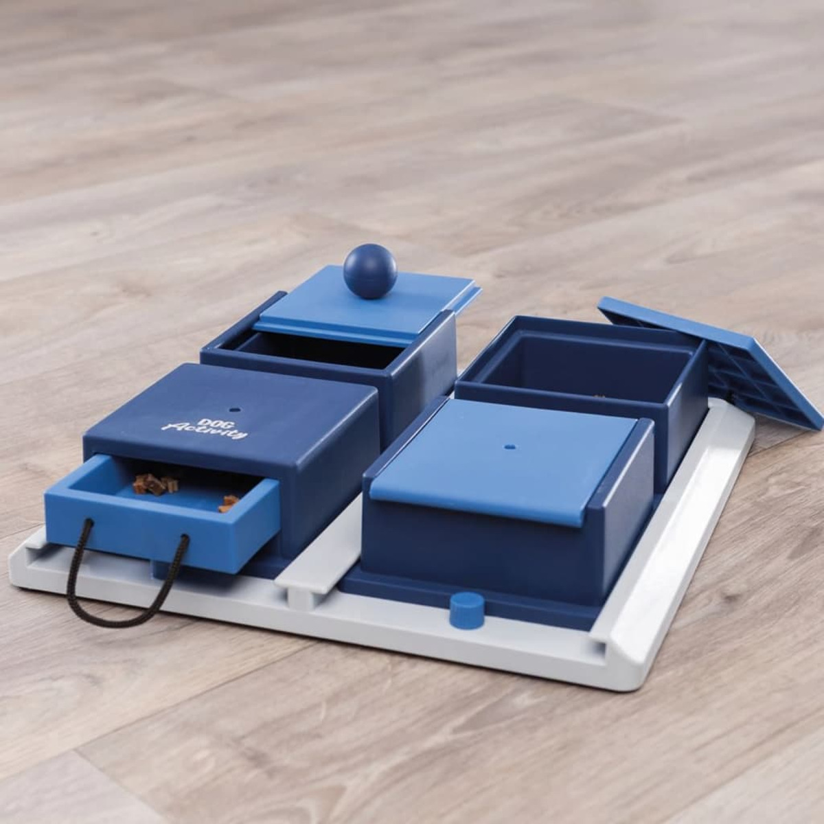 Giocattolo puzzle per cani con design blu e bianco su pavimento in legno.