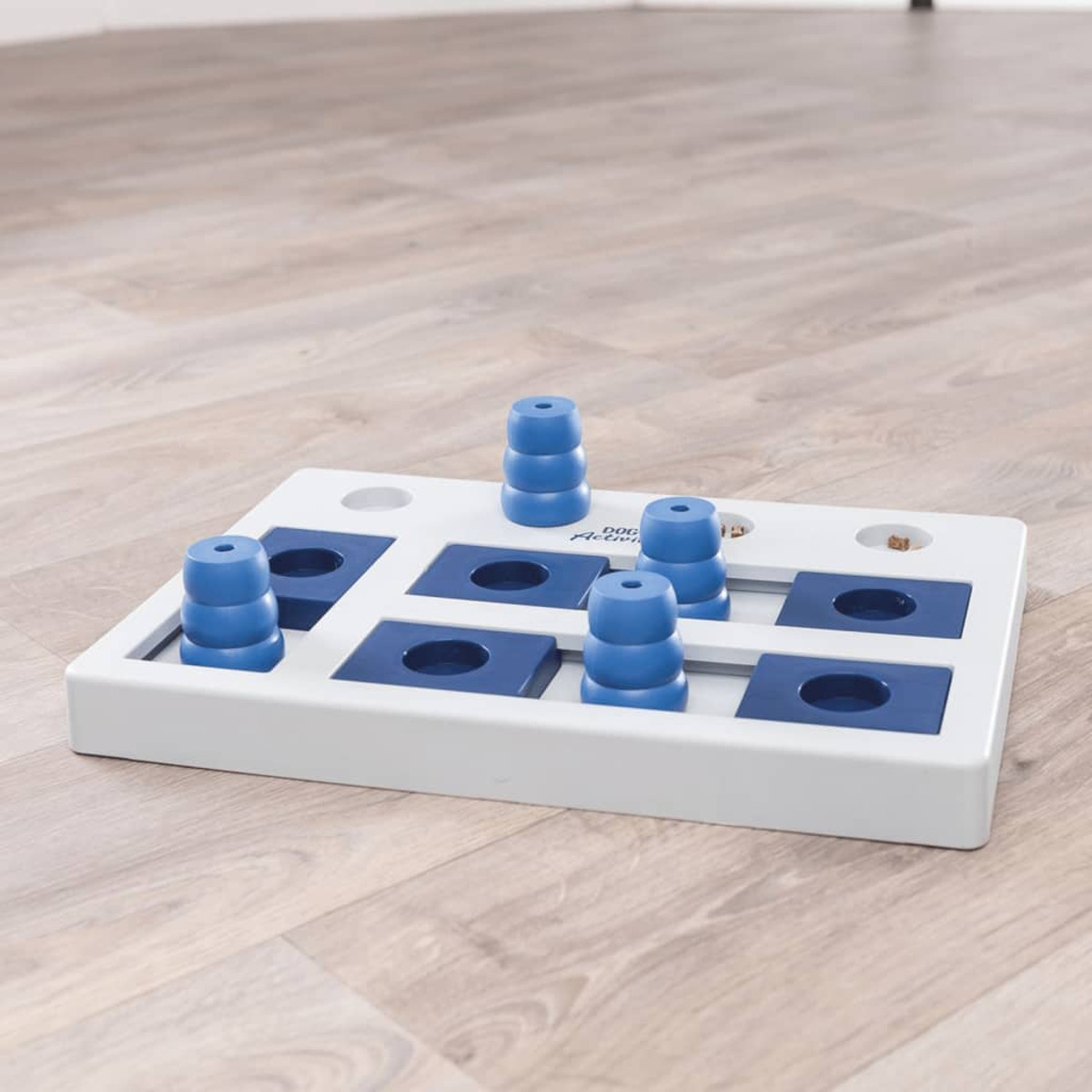 Un giocattolo puzzle per cani bianco e blu su una superficie di legno.