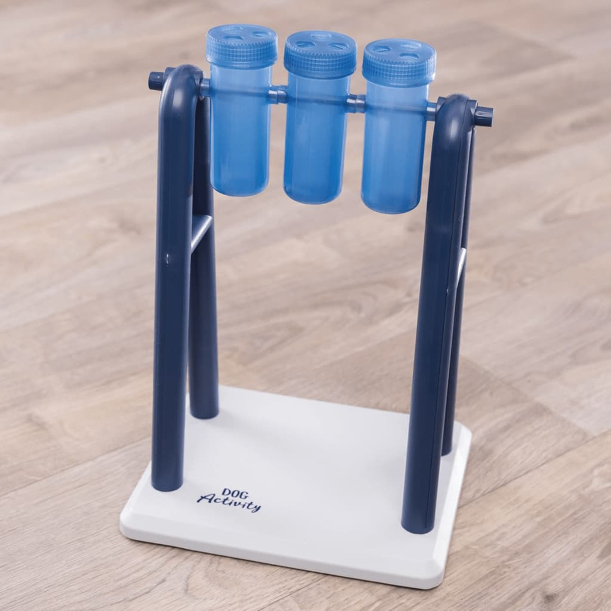 Zabawka dla psa z 3 niebieskimi butelkami na biało-niebieskiej podstawie. Drewniana podłoga.