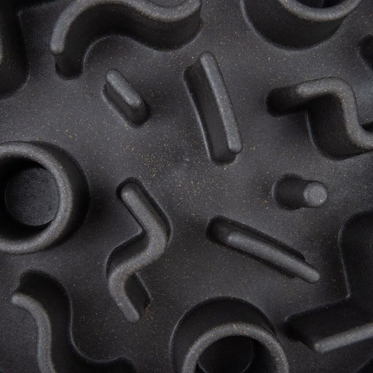 Gros plan sur un bol noir pour animaux à alimentation lente avec des motifs en relief complexes.