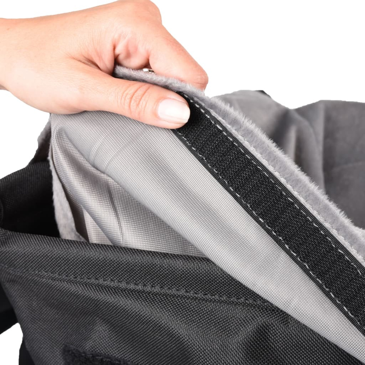 Eine Hand öffnet eine schwarze Tasche mit grauem Innenraum. Die Tasche hat Klettverschluss.