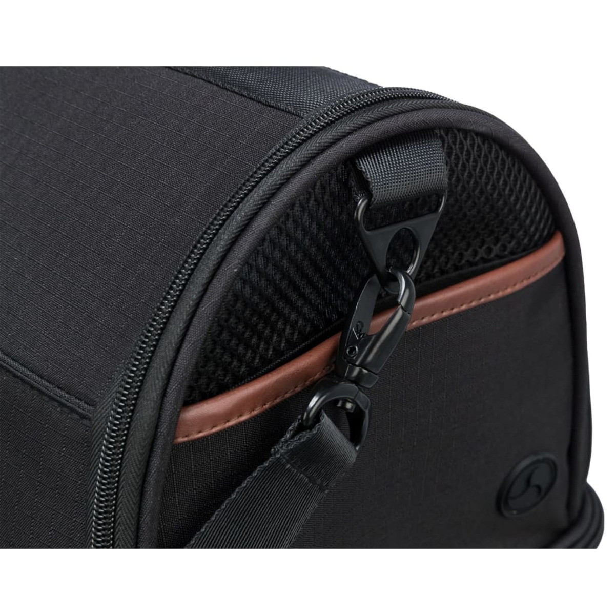 Nahaufnahme einer schwarzen Tasche mit braunem Akzent und Metallclip. Ein schwarzer Riemen ist sichtbar.