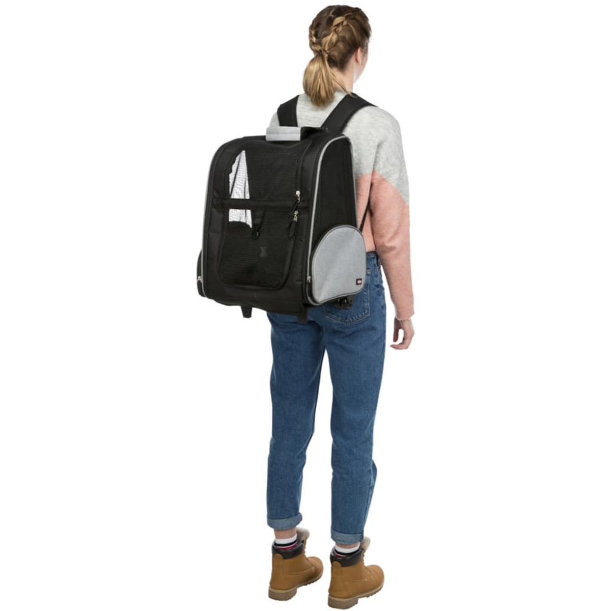 Kobieta z plecakiem, stojąca tyłem do kamery, niosąca czarny transporter dla zwierząt.