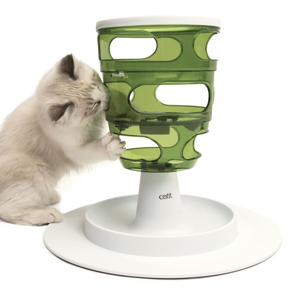 Un gatto interagisce con un distributore di cibo per gatti verde a più livelli. Sfondo bianco.