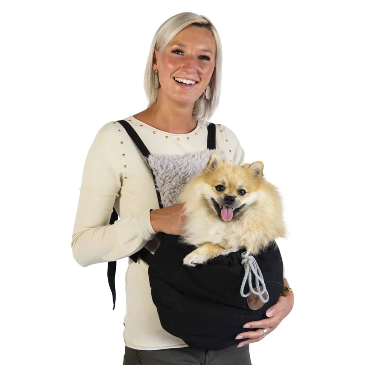 Eine Frau hält einen kleinen, flauschigen, hellbraunen Hund in einer schwarzen Tragetasche. Sie lächeln.