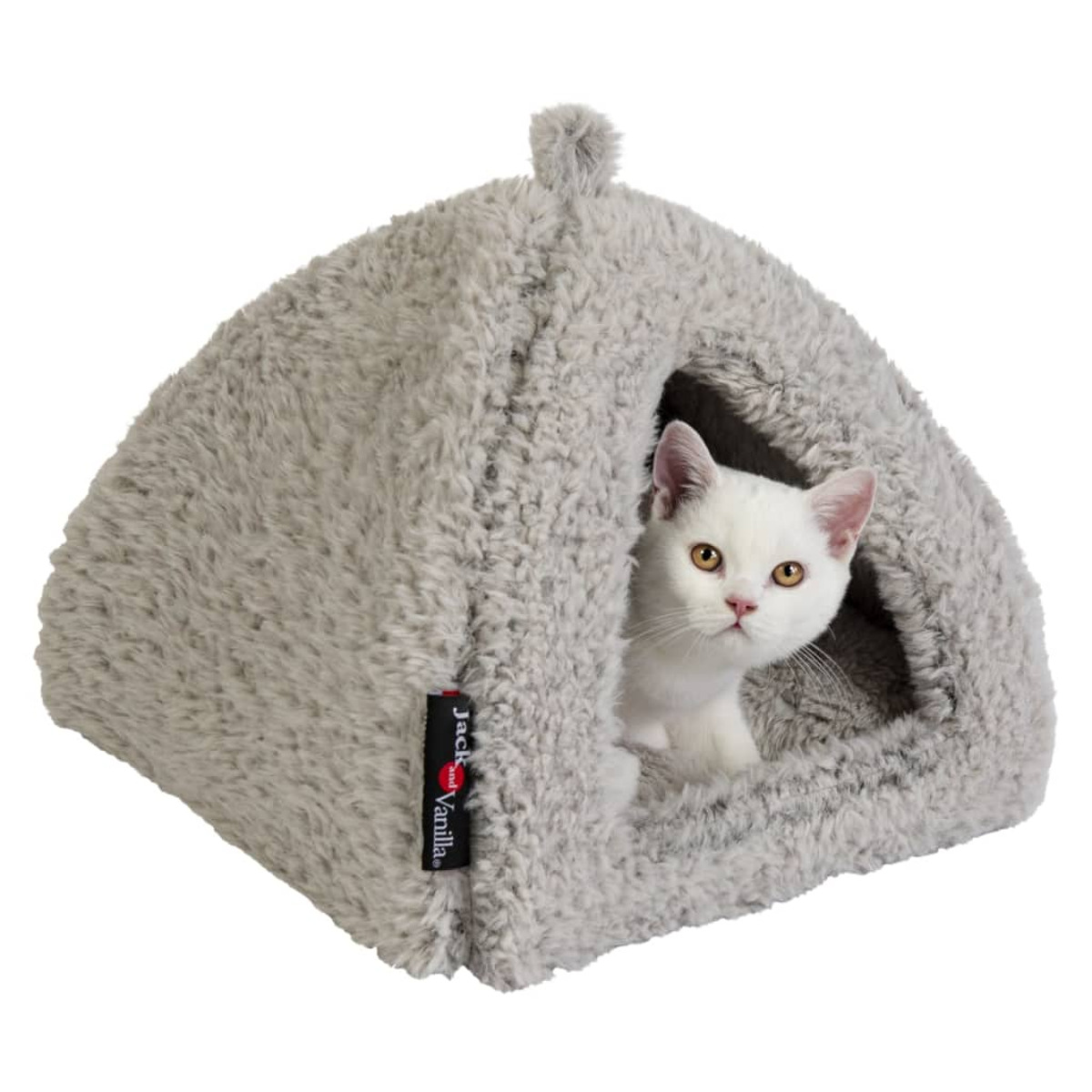 Eine weiße Katze sitzt in einem flauschigen grauen Katzenbett und schaut zum Betrachter.