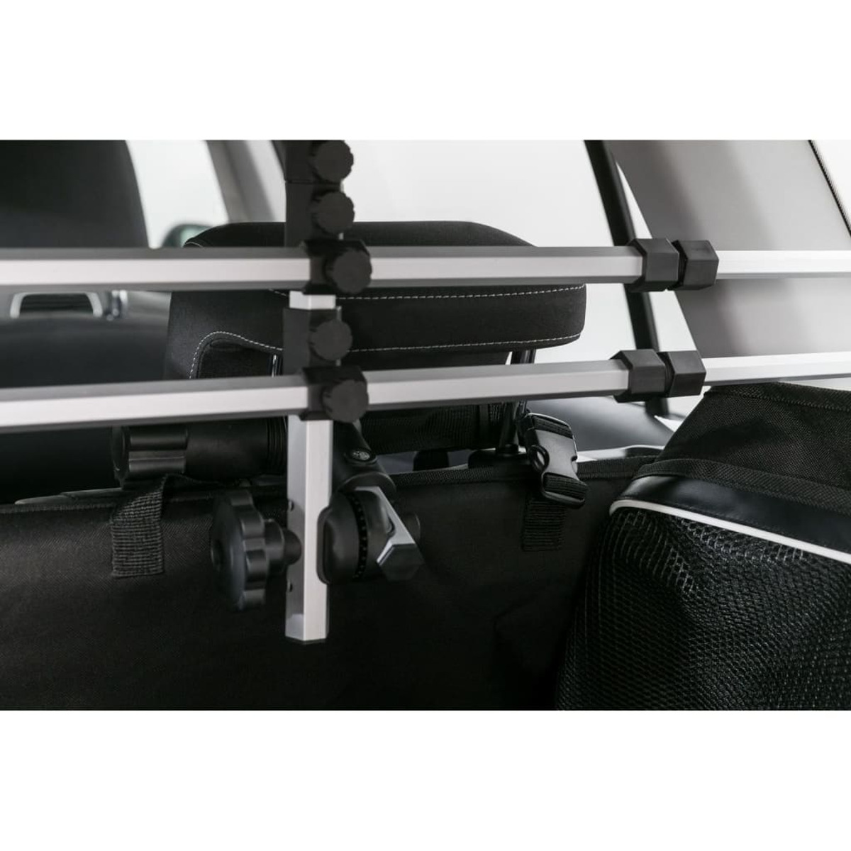 Ein Autointerieur mit einem installierten Hundezaun zwischen den Sitzen und einer schwarzen Tasche.