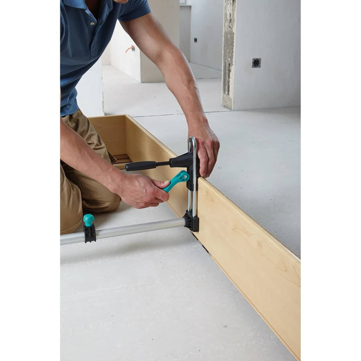 Eine Person, die eine Klemme verwendet, um eine Holzkonstruktion auf einer Baustelle zusammenzubauen.