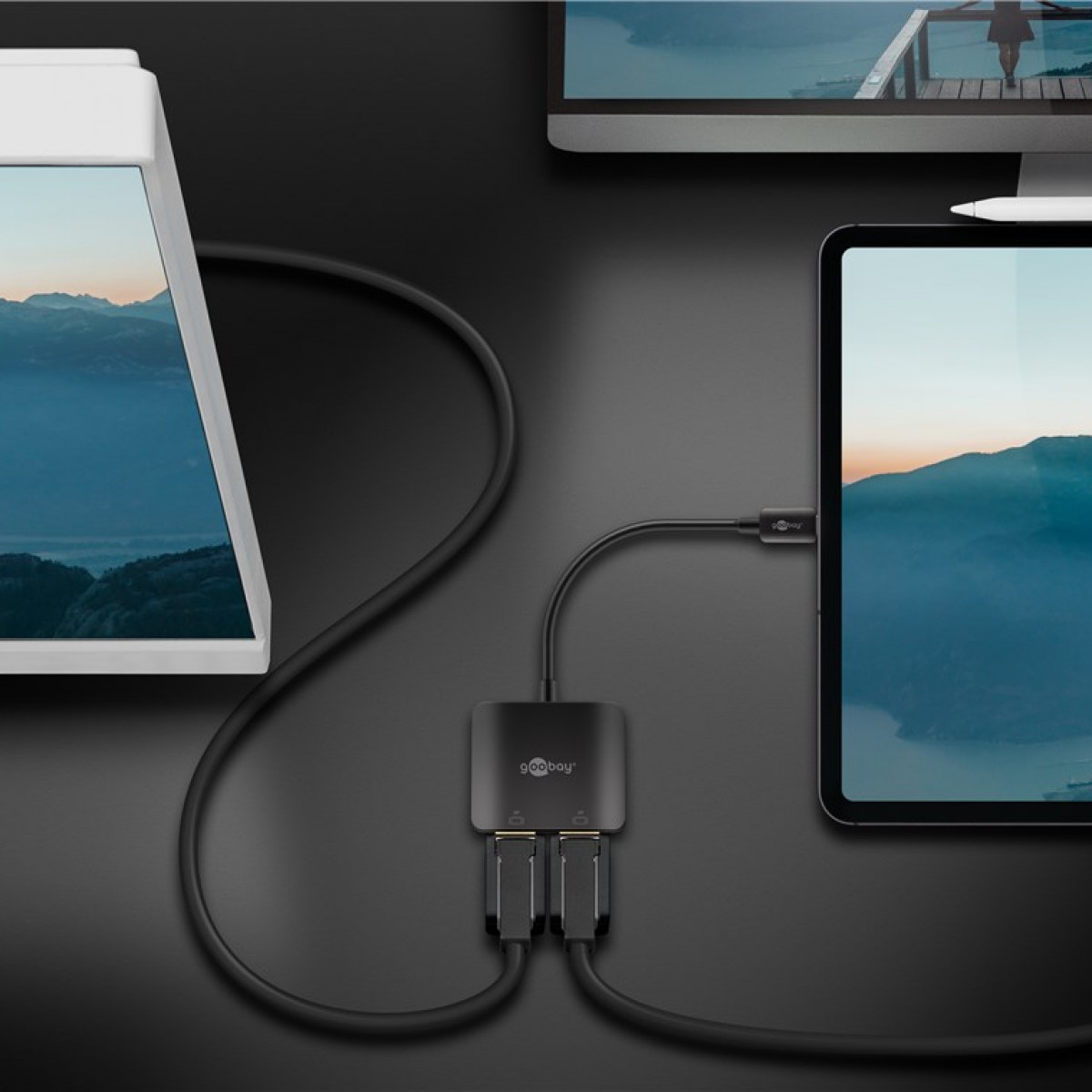Ein schwarzer Hub, der mit zwei Tablets und einem Laptop verbunden ist, auf einem schwarzen Tisch.