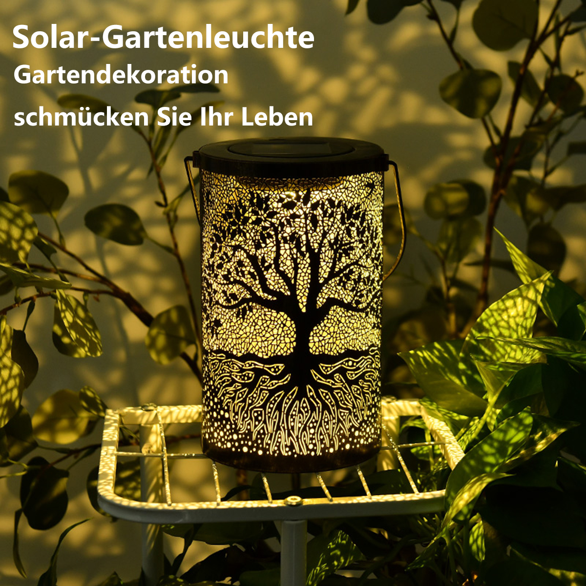 Solar-Gartenlaterne mit Baumdesign. Die Laterne steht auf einem weißen Ständer mit Pflanzen drumherum.