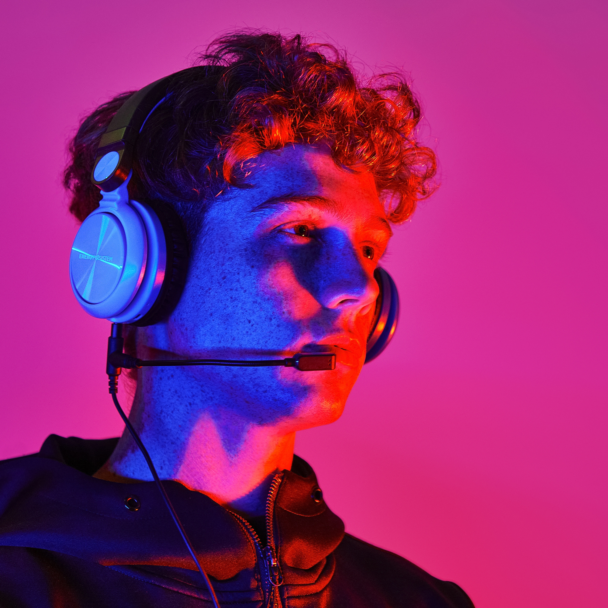 Un hombre con auriculares, iluminado por luces rojas y azules.